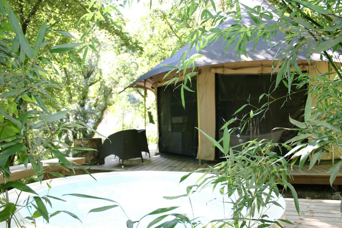 A pool area with a tent structure, surrounded by bamboo plants.
