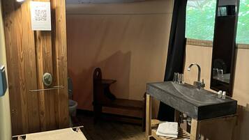 Ein kleines Badezimmer mit Holzboden, Waschbecken mit Spiegel und Toilette.