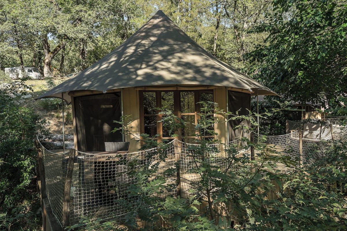 A small, enclosed pavilion with a peaked roof, surrounded by a wire fence and lush greenery.