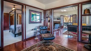 A spacious room with a large bed, a leather chair, a dining area with a table and chairs, and a view through an open doorway. - Extraordinary Capitol Hill Home! (Salt Lake City)