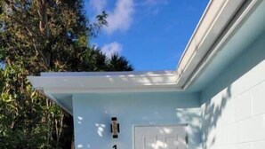 A narrow, covered walkway leading to a white door marked with the number 1. - Ocean Breezes (Lantana)