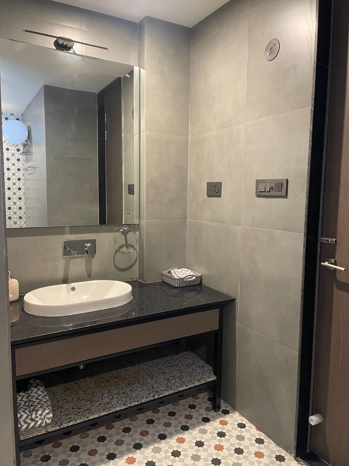 Un bagno moderno con un lavandino bianco, uno specchio e una doccia.