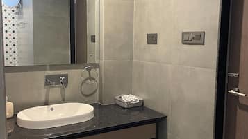 Un bagno moderno con un lavandino bianco, uno specchio e una doccia.