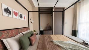 Un dormitorio con cama, almohadas, una mesita de noche y un cuadro en la pared.