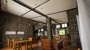 A spacious dining area with stone walls and wooden furniture. - Imbogo Diners and Lounge (Kisoro)