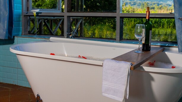 A bathtub with a towel, a wine bottle, and a glass. - Imbogo Diners and Lounge (Kisoro)