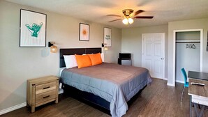 A bedroom with a bed, wooden floor, ceiling fan, and a desk with a chair. - The 409 Bolivar Beach Hotel (Port Bolivar)