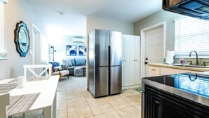 Una cocina moderna con un refrigerador de acero inoxidable, una estufa negra y gabinetes blancos.