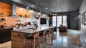 A modern kitchen with a large island, bar stools, and pendant lighting.