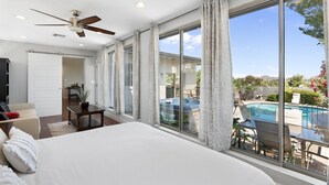 A bedroom with a large bed, a ceiling fan, a view of a swimming pool, and a balcony with outdoor seating. - Oasis Overlook, Have Fun in Pool/Hot Tub/Putt Grn (Phoenix)