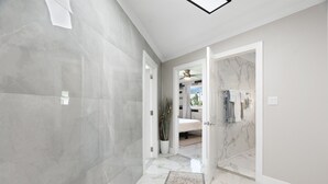 A hallway with marble flooring leading to a bathroom with a shower and a toilet. - Oasis Overlook, Have Fun in Pool/Hot Tub/Putt Grn (Phoenix)