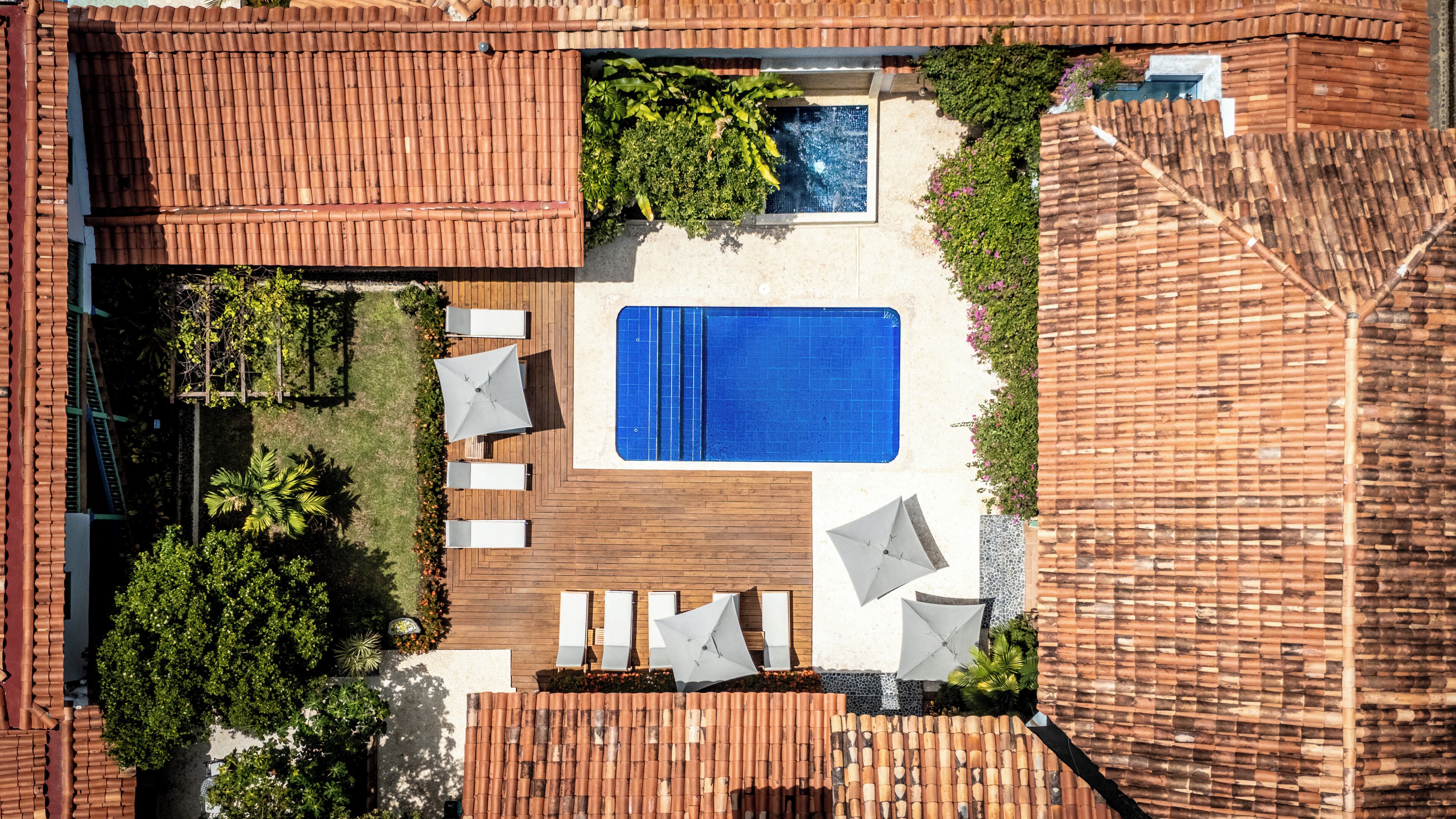 Vista aérea de una azotea con piscina, tumbonas y terraza de madera.
