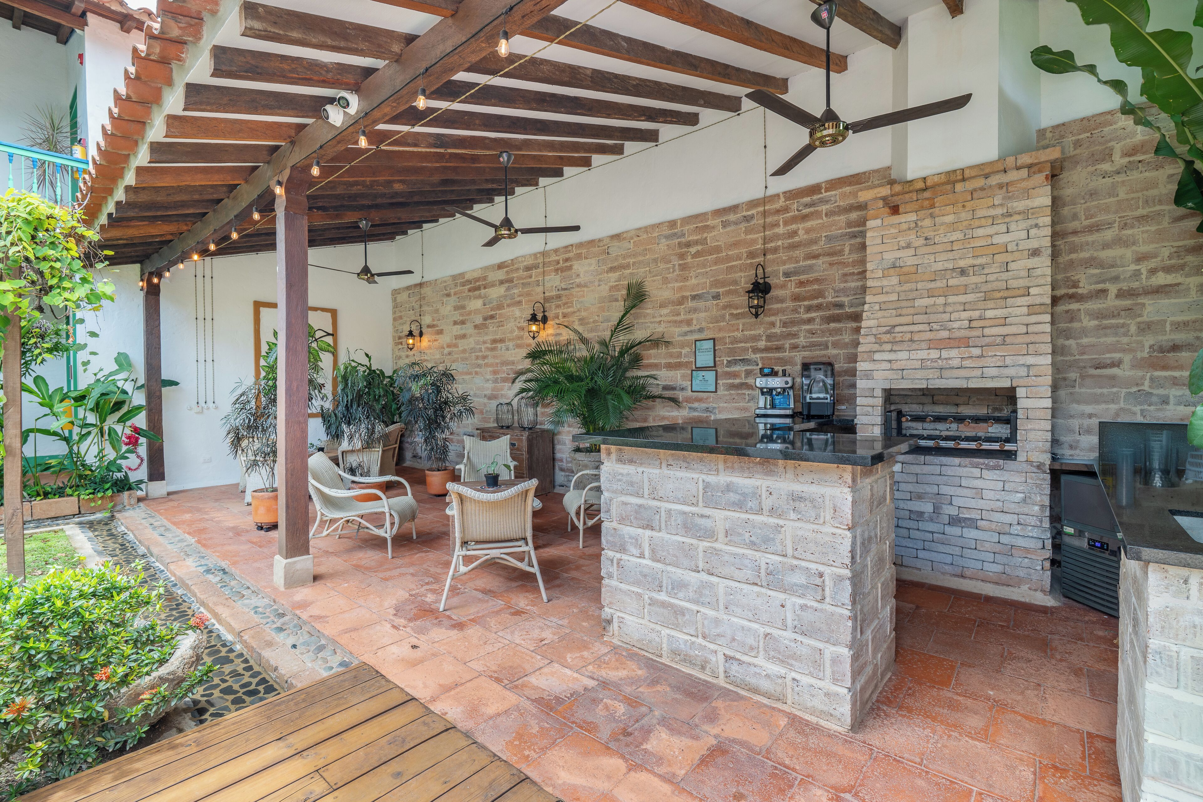An outdoor patio with a brick fireplace, seating area, and ceiling fans.