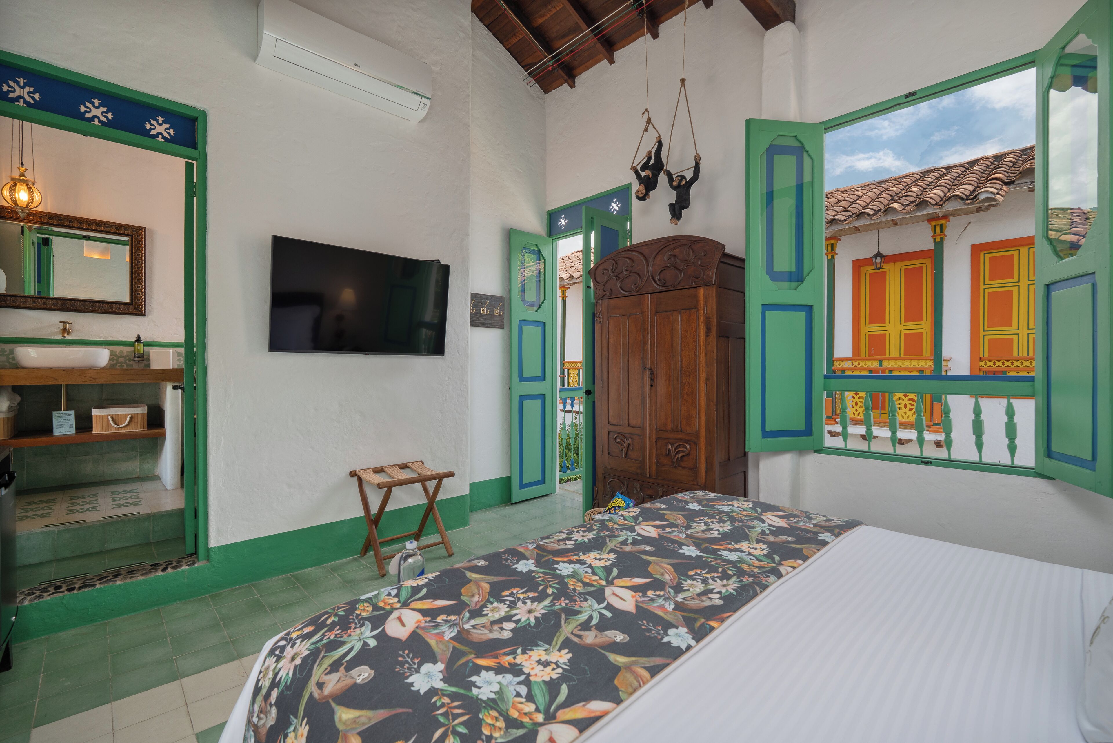 A bedroom with a bed, a TV, a wooden wardrobe, and a green door.