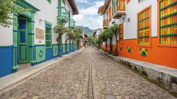 A cobblestone street lined with colorful buildings, a sign reading "Casa Corredor," and a mountain in the background.