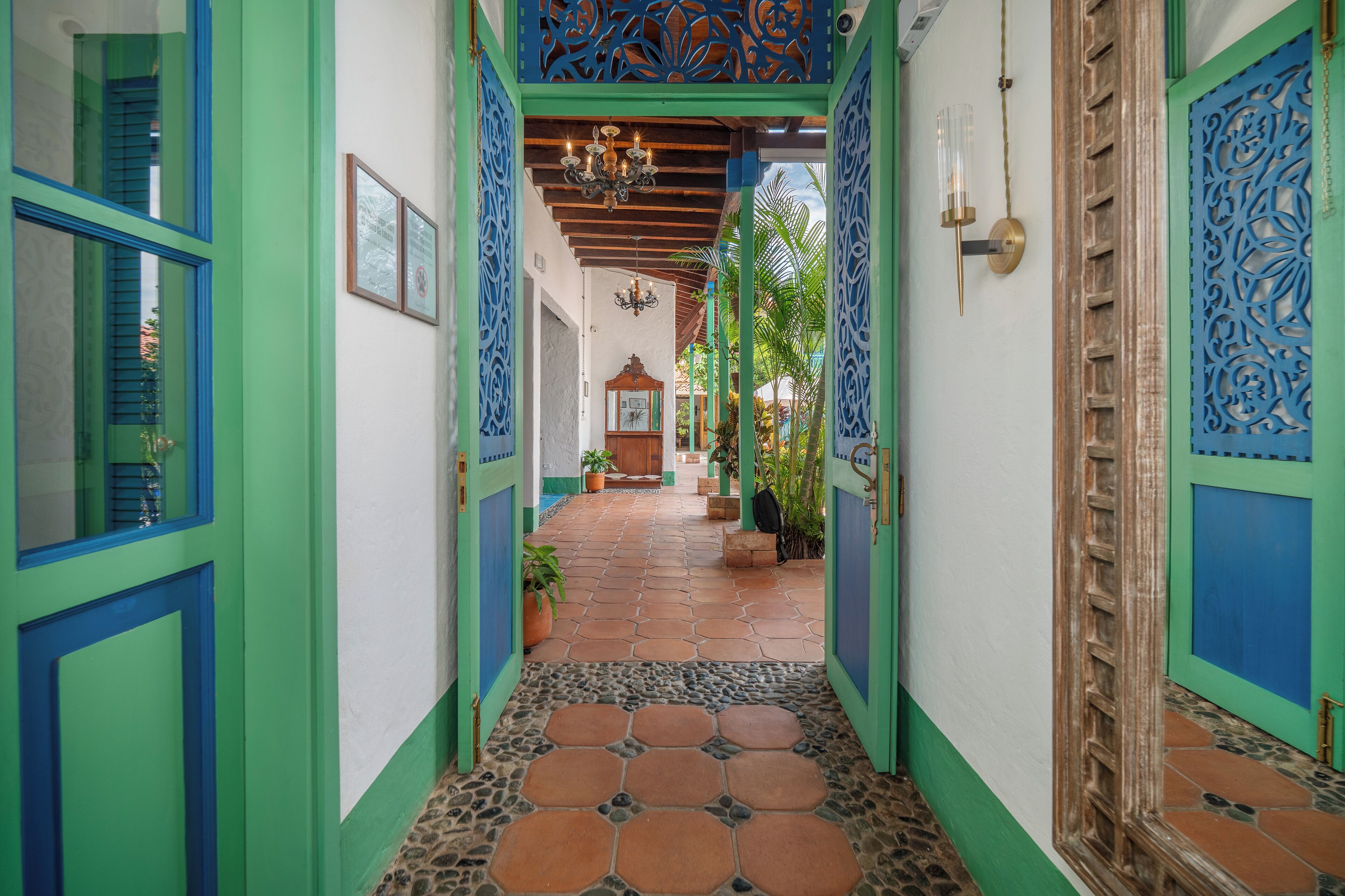A hallway with green and blue doors, a tiled floor, and a wooden door at the end.