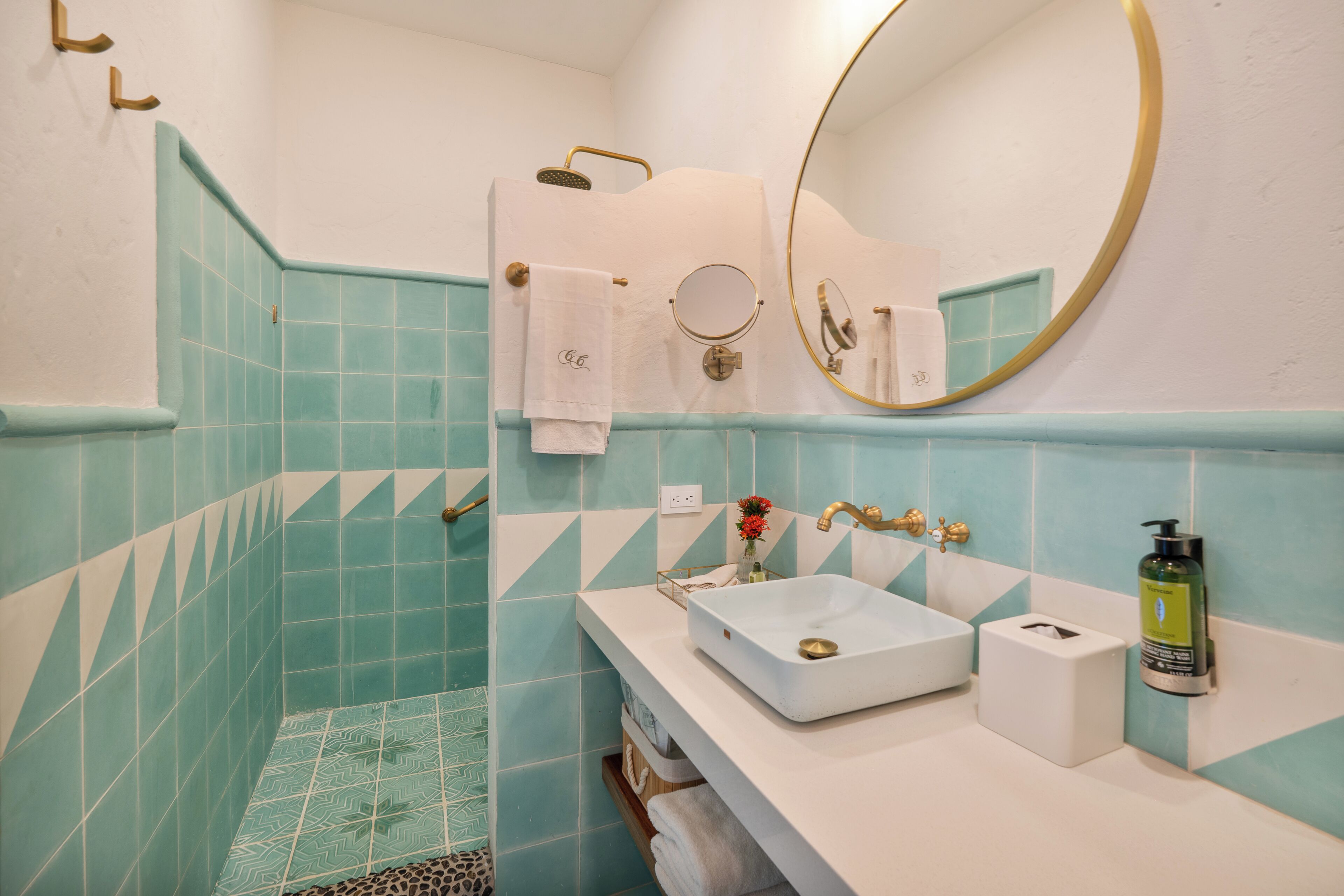 A bathroom with a white sink, a mirror, and a shower area.