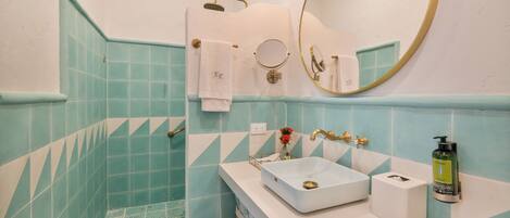 A bathroom with a white sink, a mirror, and a shower area.
