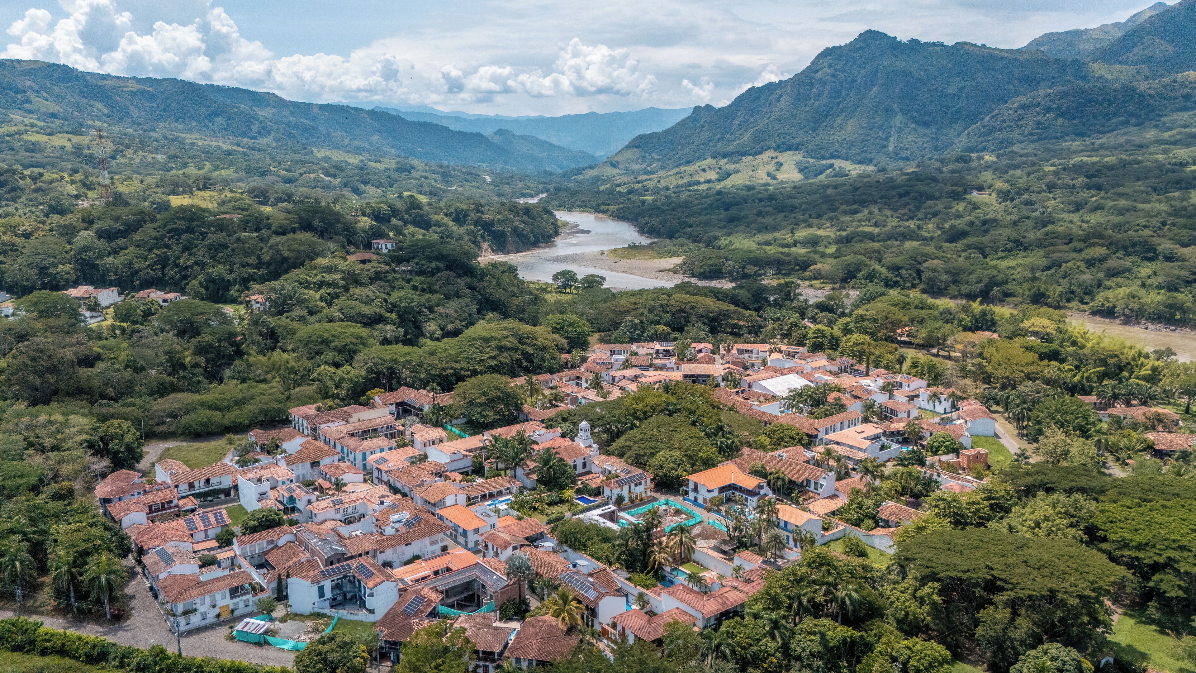 An aerial view of a town with terraced houses, a river, and surrounding hills.