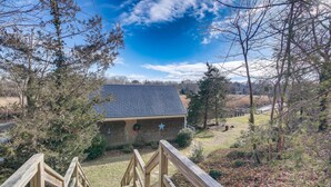 Un escalier en bois mène à un chalet doté d’un toit sombre, entouré d’arbres et surplombé par un ciel dégagé.