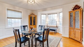 A dining area with a glass table surrounded by chairs, a wooden cabinet with glass doors, and a patterned rug. - Welcome To Tigertown! 4 Bd House (Towson)