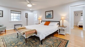 A spacious bedroom with a large bed, two bedside tables with lamps, a chair, and a patterned rug. - Welcome To Tigertown! 4 Bd House (Towson)
