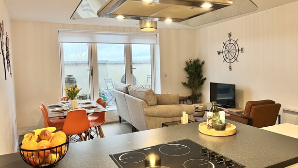 Een moderne keuken met een centraal eiland, een eethoek met oranje stoelen en een groot raam met uitzicht.