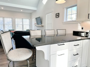 Una cocina moderna con una isla central, muebles blancos y una zona de comedor con sillas.