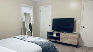 Quarto com cama, TV sobre suporte de madeira e armário.