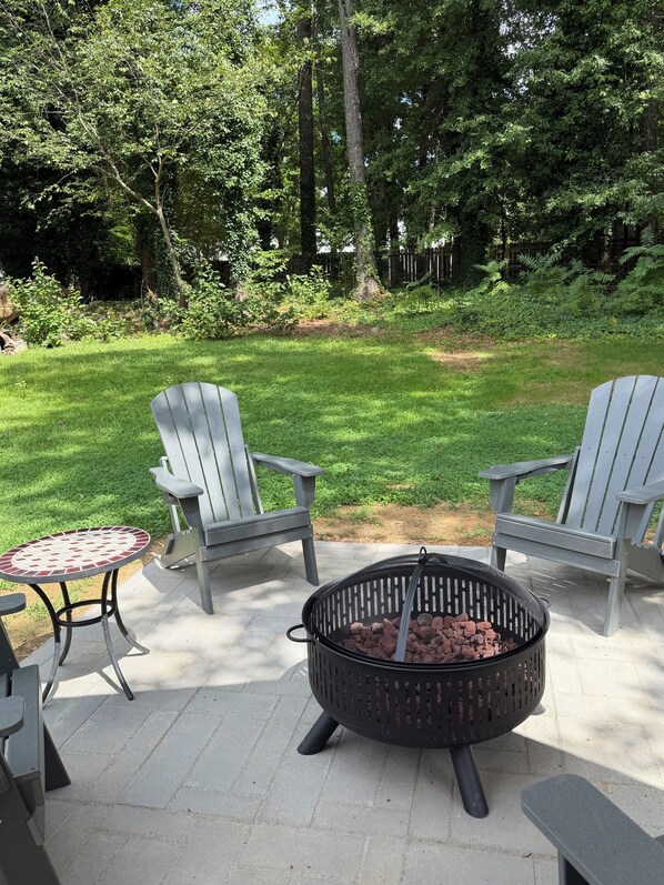 An outdoor patio with two Adirondack chairs, a round table, and a fire pit. - 2king beds, 1 queen, 1 full (Stone Mountain)
