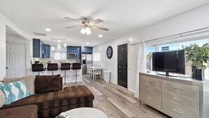 A modern living room with a brown sofa, a coffee table, and a TV on a cabinet. - Modern City Ranch Family Home Access by Dirt Road (Palmdale)