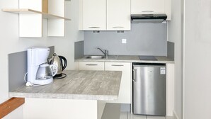 A compact kitchen with white cabinets, a stainless steel dishwasher, and a coffee maker. - Large studio with breathtaking views of the Baie des Sables (Les Sables-d´Olonne)