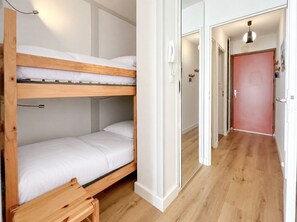Ein Schlafraum mit Etagenbett, Holzbettgestell, Nachttisch und Telefon.