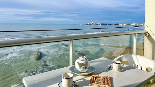 A balcony with a table set for two, overlooking a beach and ocean. - Large studio with breathtaking views of the Baie des Sables (Les Sables-d´Olonne)