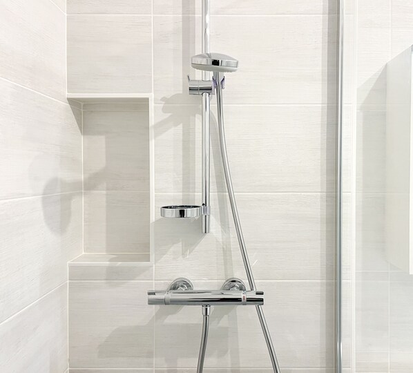 Eine moderne Dusche mit Chromarmaturen und einer Glasabtrennung.