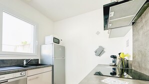 A modern kitchen with a built-in oven, a refrigerator, a microwave, and a coffee maker.