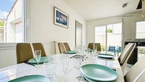 A dining area with a long table set for six, including plates, cutlery, and glasses.