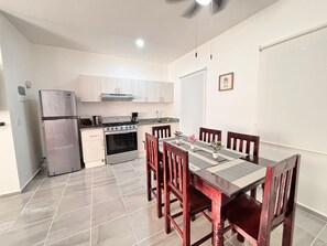 Compact kitchen with a gas stove, oven, and dining area with a wooden table and chairs.