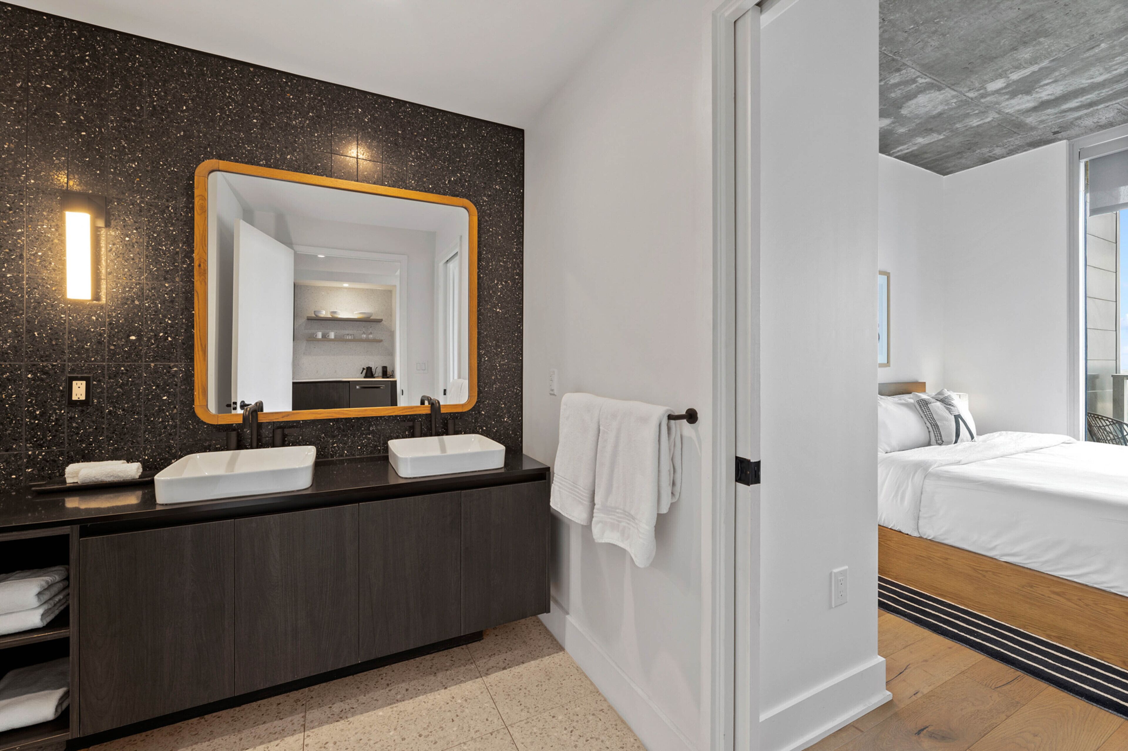 Une salle de bain moderne avec un double vasque, des meubles de couleur sombre et un grand miroir.