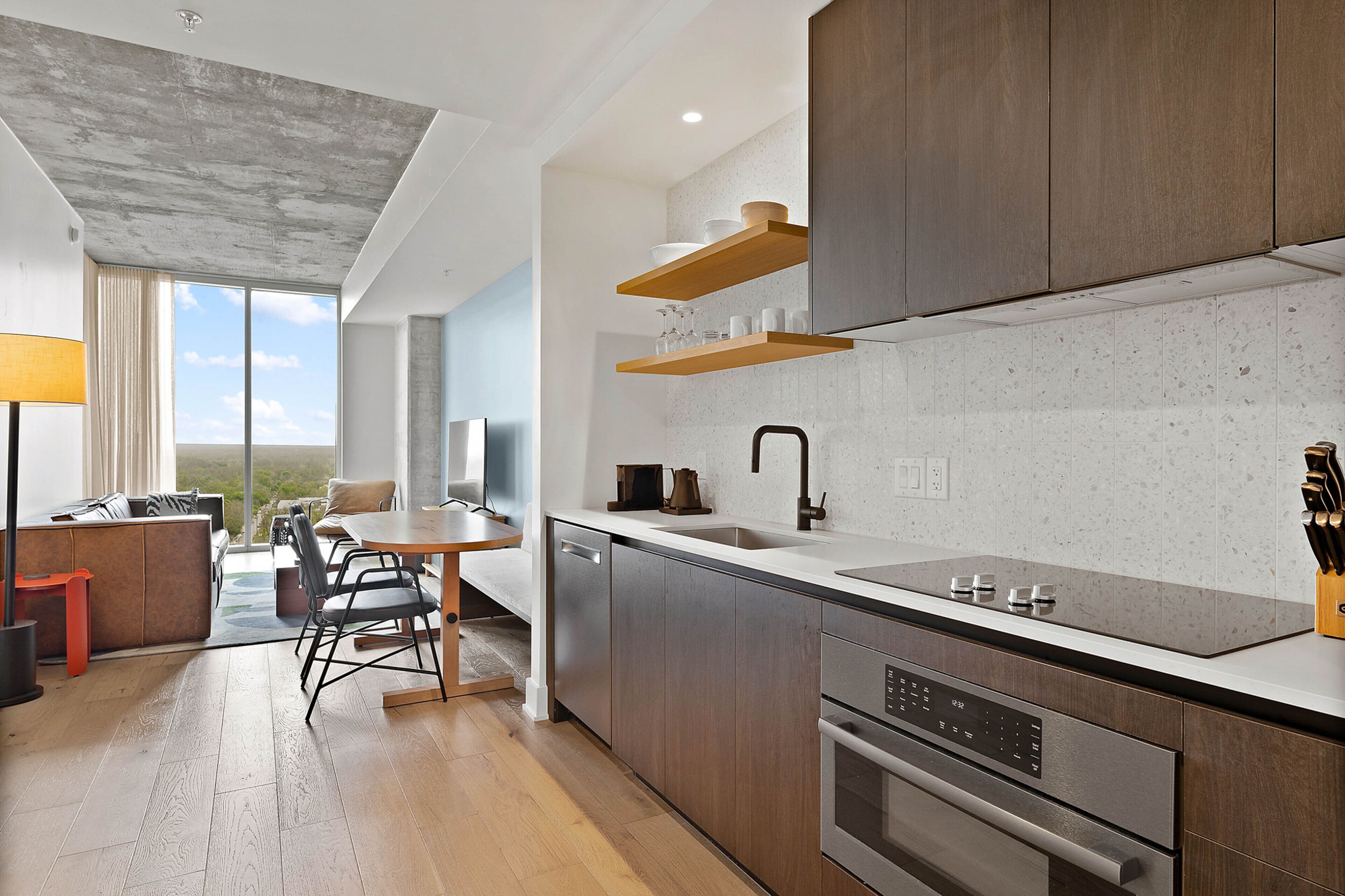 A modern kitchen with wooden cabinets, a stainless steel dishwasher, and a built-in oven.