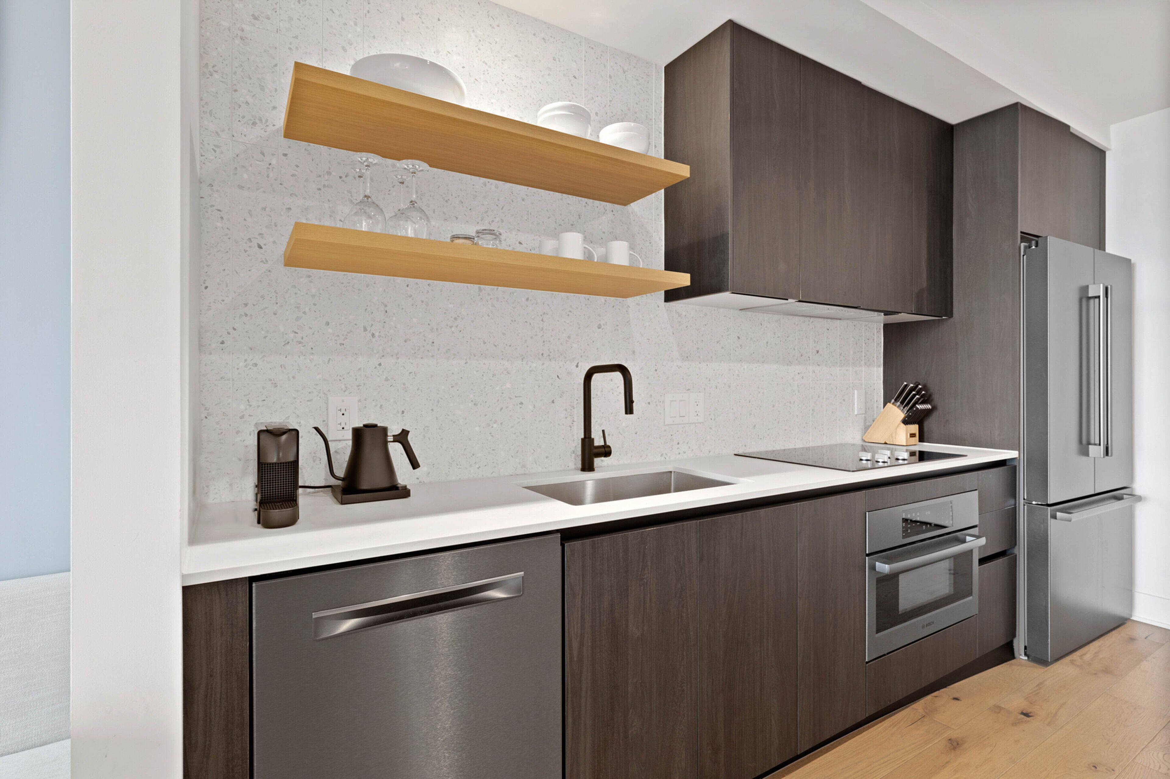 Una cocina moderna con armarios de madera oscura, electrodomésticos de acero inoxidable y encimera blanca.