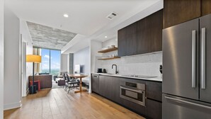A modern kitchen with dark cabinets, stainless steel appliances, and a wooden dining area with a view. - 20th FL 1BR | Heated Pool | Gym | Bar | Balcony (Austin)