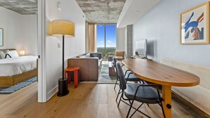 A modern hotel room with a bed, a sofa, a dining table, and a TV. - 20th FL 1BR | Heated Pool | Gym | Bar | Balcony (Austin)