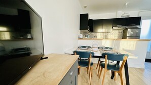 Una cocina moderna con comedor. Cuenta con encimera de madera, una mesa de comedor con sillas y electrodomésticos integrados.