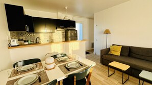 Un espacio habitable compacto con comedor, kitchenette y sofá.