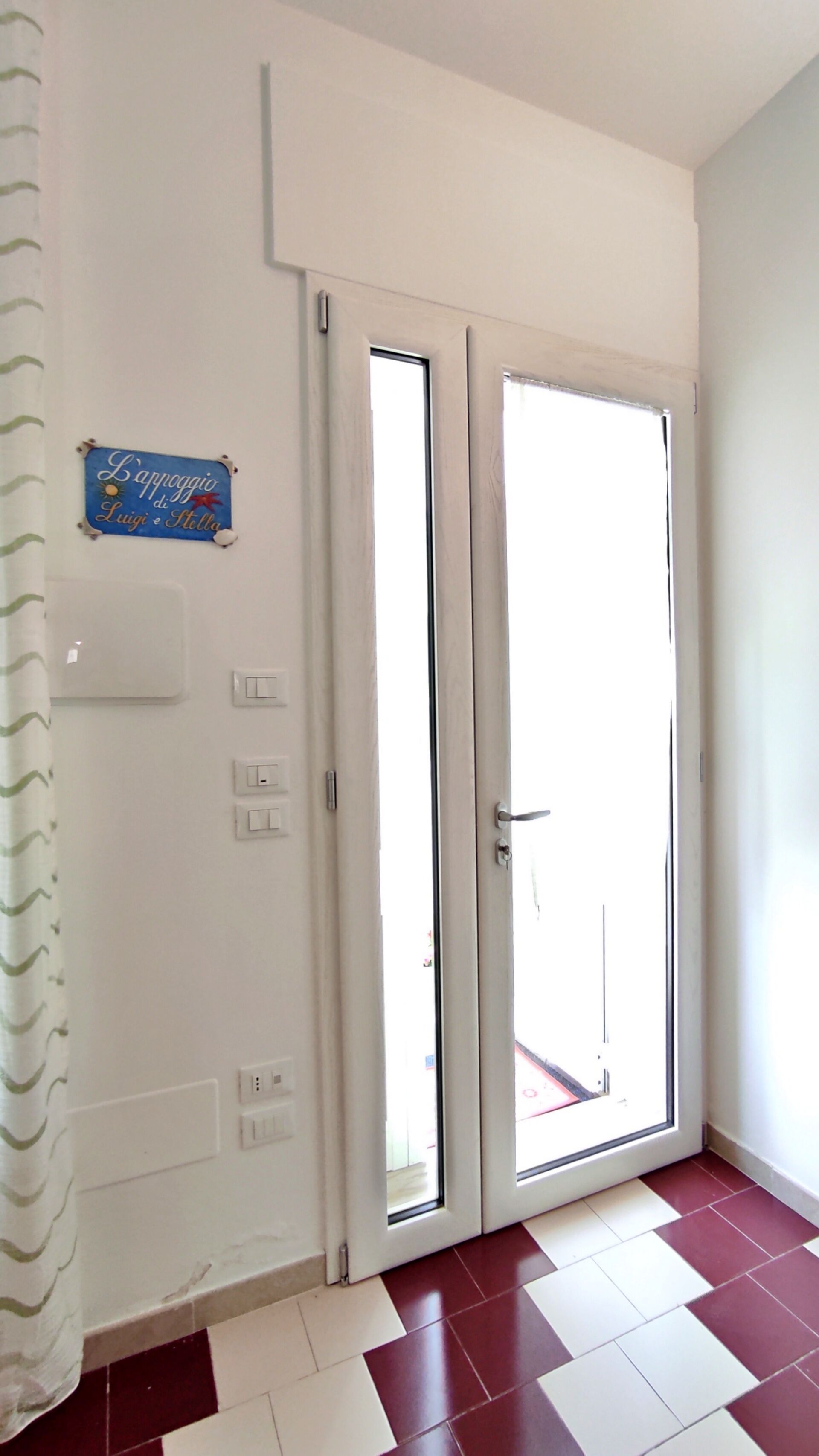 A room with a double door, a light switch, and a power outlet on the wall.