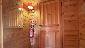 Un pasillo de madera con un extintor montado en la pared y una puerta de madera cerrada.