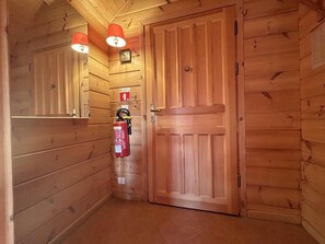 Een houten gang met een brandblusser aan de muur en een gesloten houten deur.