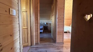Un pasillo de madera que conduce a un dormitorio con una cama y una mesita de noche.