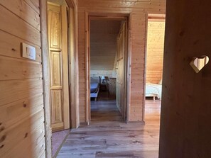 Een houten gang die leidt naar een slaapkamer met een bed en een nachtkastje.